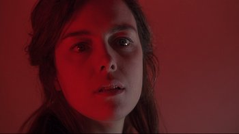 Movie still from “Below” (2002), directed by David Twohy – A woman's face in red light; Close Up shot, Low angle