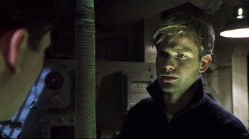 Movie still from “Below” (2002), directed by David Twohy – A young man is standing in a dark room; Close Up shot, Low angle
