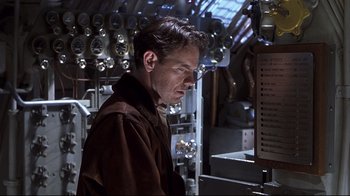Movie still from “Below” (2002), directed by David Twohy – A man standing in front of a machine; Medium shot, Low angle