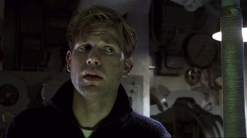 Movie still from “Below” (2002), directed by David Twohy – A young man is looking into the distance; Close Up shot, Low angle