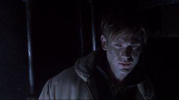 Movie still from “Below” (2002), directed by David Twohy – A young man in a coat is looking at the camera; Close Up shot, Low angle