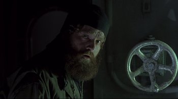 Movie still from “Below” (2002), directed by David Twohy – A man with a long beard and a black hat; Close Up shot, Low angle