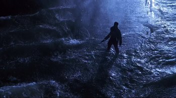 Movie still from “Below” (2002), directed by David Twohy – A man in a black jacket walking through a flooded area; Extreme Wide shot, High angle