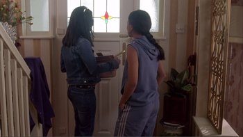 Movie still from “Bend It Like Beckham” (2002), directed by Gurinder Chadha – Two young women standing in front of a door; Medium shot, High angle