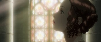 A woman with curly hair looking out a stained glass window
