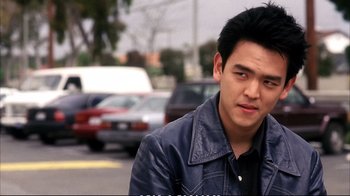Movie still from “Better Luck Tomorrow” (2002), directed by Justin Lin – A man in a leather jacket standing on the side of the road; Close Up shot, Over the shoulder angle