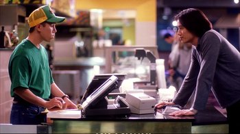 Movie still from “Better Luck Tomorrow” (2002), directed by Justin Lin – Two people sitting at a counter with a printer; Medium shot, Over the shoulder angle