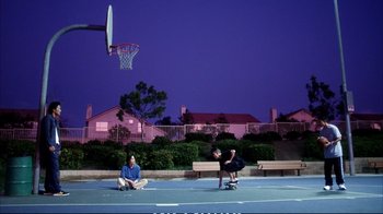 Movie still from “Better Luck Tomorrow” (2002), directed by Justin Lin – Two people are sitting on the ground near a basketball hoop; Wide shot, Low angle