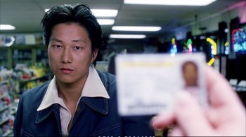 Movie still from “Better Luck Tomorrow” (2002), directed by Justin Lin – A person taking a picture of a man in a blue jacket; Close Up shot, Over the shoulder angle