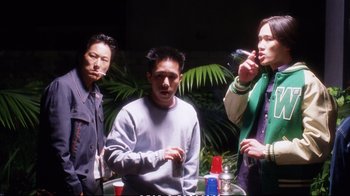 Movie still from “Better Luck Tomorrow” (2002), directed by Justin Lin – A group of people standing around a table; Medium shot, Low angle