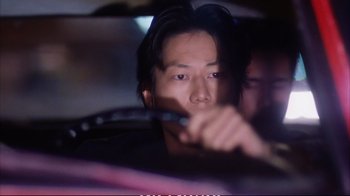 Movie still from “Better Luck Tomorrow” (2002), directed by Justin Lin – A man with long black hair is holding a pen; Close Up shot, Low angle