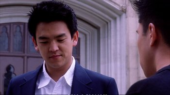 Movie still from “Better Luck Tomorrow” (2002), directed by Justin Lin – A man in a suit and tie standing in front of a building; Close Up shot, High angle