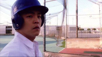 Movie still from “Better Luck Tomorrow” (2002), directed by Justin Lin – A baseball player wearing a blue helmet in front of a baseball field; Close Up shot, Low angle