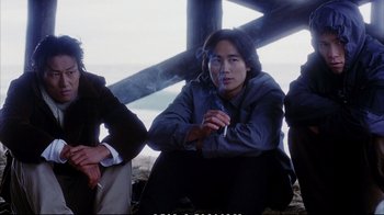 Movie still from “Better Luck Tomorrow” (2002), directed by Justin Lin – A man smoking a cigarette while sitting next to another man; Medium shot, Low angle