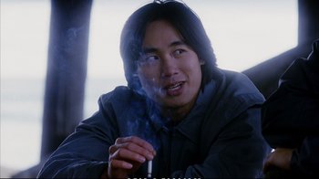 Movie still from “Better Luck Tomorrow” (2002), directed by Justin Lin – A man smoking a cigarette while sitting on a couch; Close Up shot, High angle