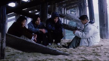 Movie still from “Better Luck Tomorrow” (2002), directed by Justin Lin – A group of young men sitting on top of a sandy beach; Wide shot, High angle