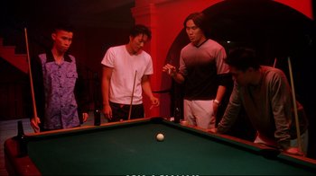 Movie still from “Better Luck Tomorrow” (2002), directed by Justin Lin – A group of young men standing around a pool table; Medium shot, High angle