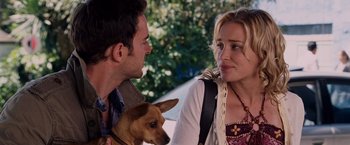 Movie still from “Beverly Hills Chihuahua” (2008), directed by Raja Gosnell – A man and a woman sitting next to each other with a dog; Close Up shot, Over the shoulder angle