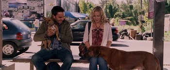Movie still from “Beverly Hills Chihuahua” (2008), directed by Raja Gosnell – A man and a woman sitting on a bench petting a dog; Medium shot, Over the shoulder angle