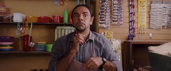 Movie still from “Beverly Hills Chihuahua” (2008), directed by Raja Gosnell – A man in a gray shirt and brown apron is holding his hands to his face; Medium shot, Low angle