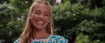 Movie still from “Beverly Hills Chihuahua” (2008), directed by Raja Gosnell – A woman smiles brightly while standing in front of trees; Close Up shot, Low angle