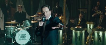 Movie still from “Beyond the Sea” (2004), directed by Kevin Spacey – A man in a black suit is singing into a microphone; Medium shot, High angle