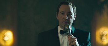 Movie still from “Beyond the Sea” (2004), directed by Kevin Spacey – A man in a tuxedo is holding a microphone; Close Up shot, Over the shoulder angle