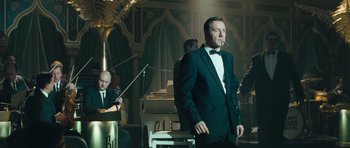 Movie still from “Beyond the Sea” (2004), directed by Kevin Spacey – A man in a tuxedo smoking a cigarette in front of other musicians; Medium shot, Low angle
