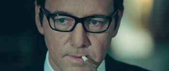 Movie still from “Beyond the Sea” (2004), directed by Kevin Spacey – A person wearing glasses and smoking a cigarette; Close Up shot, Low angle