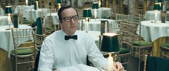 Movie still from “Beyond the Sea” (2004), directed by Kevin Spacey – A man sitting at a table in front of candles; Close Up shot, Over the shoulder angle
