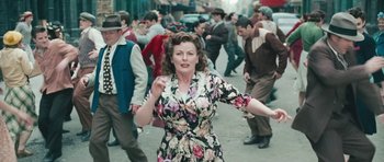 Movie still from “Beyond the Sea” (2004), directed by Kevin Spacey – A woman in a floral print dress dancing in the middle of a crowd; Medium shot, High angle