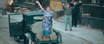 Movie still from “Beyond the Sea” (2004), directed by Kevin Spacey – An older woman standing on the back of a car; Wide shot, High angle
