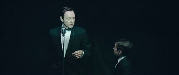 Movie still from “Beyond the Sea” (2004), directed by Kevin Spacey – A man in a suit and tie standing next to another man; Medium shot, Over the shoulder angle