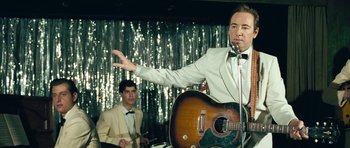 Movie still from “Beyond the Sea” (2004), directed by Kevin Spacey – A man in a white suit is holding a guitar; Medium shot, Over the shoulder angle