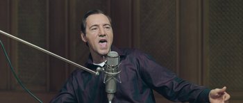 Movie still from “Beyond the Sea” (2004), directed by Kevin Spacey – A man is singing into a microphone in front of a wall; Close Up shot, Low angle