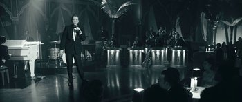 Movie still from “Beyond the Sea” (2004), directed by Kevin Spacey – A black and white photo of a man in a suit and bow tie; Wide shot, High angle