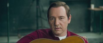 Movie still from “Beyond the Sea” (2004), directed by Kevin Spacey – A man in a red shirt is holding a guitar; Close Up shot, Low angle
