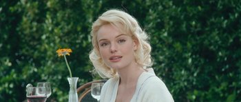 Movie still from “Beyond the Sea” (2004), directed by Kevin Spacey – A woman sitting at a table with a flower in a vase; Close Up shot, Over the shoulder angle