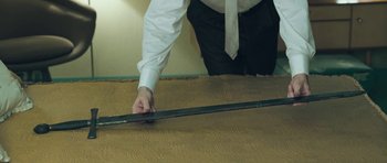 Movie still from “Beyond the Sea” (2004), directed by Kevin Spacey – A man in a white shirt and black pants holding a metal bar; Medium shot, High angle