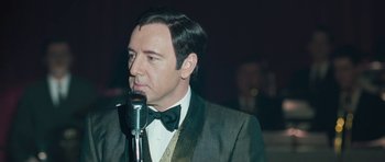 Movie still from “Beyond the Sea” (2004), directed by Kevin Spacey – A man in a suit and bow tie is talking into a microphone; Close Up shot, Over the shoulder angle