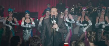 Movie still from “Beyond the Sea” (2004), directed by Kevin Spacey – A man is holding a microphone in front of a group of women; Medium shot, Over the shoulder angle