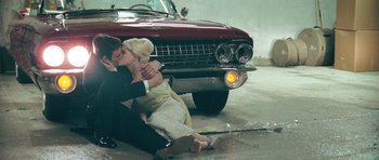 Movie still from “Beyond the Sea” (2004), directed by Kevin Spacey – A man and a woman kissing in front of an old car; Wide shot, High angle