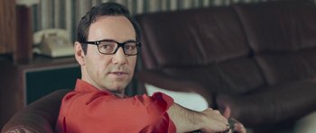 Movie still from “Beyond the Sea” (2004), directed by Kevin Spacey – A person wearing glasses and a red shirt; Close Up shot, Over the shoulder angle