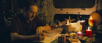 Movie still from “Beyond the Sea” (2004), directed by Kevin Spacey – A man sitting at a table writing on a piece of paper; Medium shot, High angle