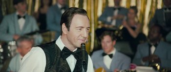 Movie still from “Beyond the Sea” (2004), directed by Kevin Spacey – A person holding a microphone; Close Up shot, Over the shoulder angle