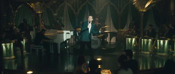 Movie still from “Beyond the Sea” (2004), directed by Kevin Spacey – A man singing into a microphone in front of an audience; Wide shot, Over the shoulder angle