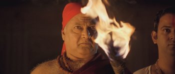 A man in a red turban is holding a fire