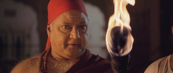 An old man wearing a red hat is looking at the camera