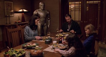 Movie still from “Bicentennial Man” (1999), directed by Chris Columbus – Three people are sitting at a table with plates of food; Wide shot, High angle