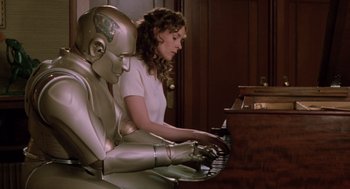 A woman sitting next to a robot playing a piano